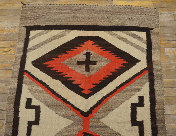 Geometric flatwoven rug in cream, gray, brown, and orange, featuring a serrated central diamond design.