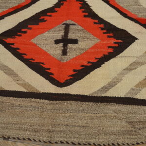 Flatwoven rug featuring large red-orange, brown, and cream geometric diamonds on wood floor.