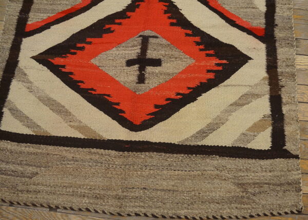 Flatwoven rug featuring large red-orange, brown, and cream geometric diamonds on wood floor.