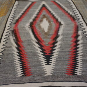 Gray, red, black, and white serrated diamond runner rug centered on rustic plank flooring.