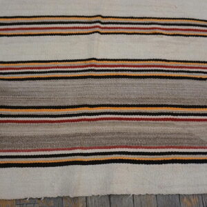 Cream and grey flat-weave rug featuring thin stripes of black, red, and yellow on wood flooring.