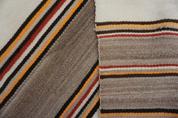 Two overlapping sections of flatweave rug display textured taupe fields and narrow stripes in cream, red, and orange.