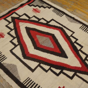 Cream, red, black, and gray flatweave rug featuring a large central concentric diamond design on wood flooring.