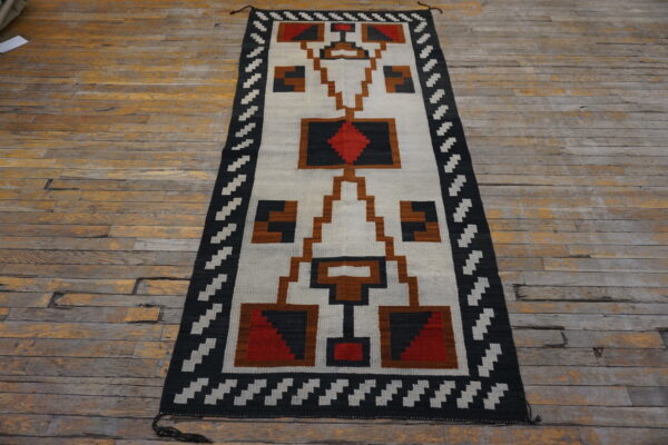 Geometric flatweave runner featuring black, white, brown, and red patterns on rustic wood flooring.