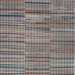 Multicolored flatweave rug with stripes and checks on natural wood plank flooring.