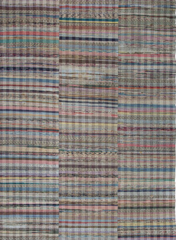 Multicolored flatweave rug with stripes and checks on natural wood plank flooring.