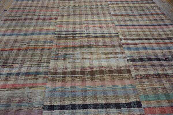Multicolor flatweave rug with horizontal stripes and checkered patches on light wood planks.
