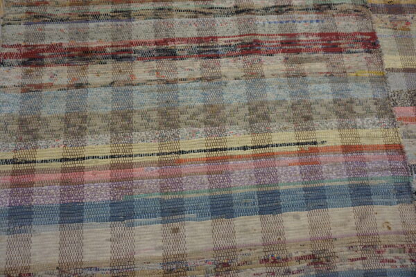Muted multicolored flat-weave rug with horizontal stripes and a patchwork checkerboard texture.