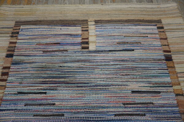 Variegated flatweave rug with horizontal blue and white stripes bordered by beige and brown accents.