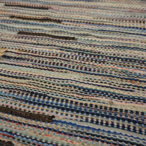Close-up of a textured low-pile rug with colorful horizontal stripes primarily in blue, white, and dark hues.