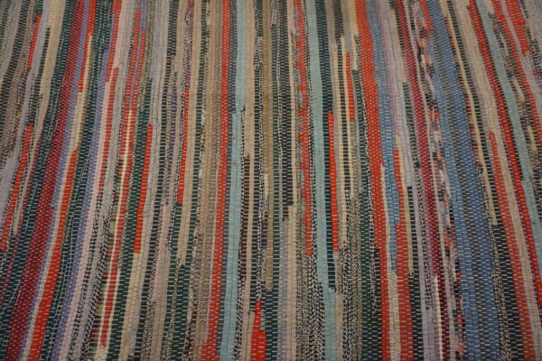 Flatwoven rug featuring vertical multicolored strips in red, blue, teal, gray, and earthy tones.