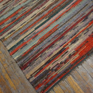 Multicolor striped rag rug with visible woven texture lying on distressed wooden plank flooring.
