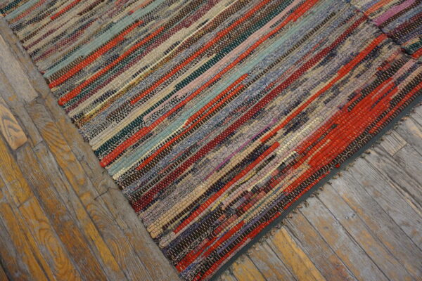 Multicolor striped rag rug with visible woven texture lying on distressed wooden plank flooring.