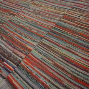 Multicolored striped flatweave rag rug with visible panel seams rests on rustic gray wood flooring.
