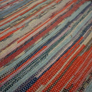 Chunky flatweave rag rug with horizontal stripes of woven red, blue, gray, and multicolored fabric pieces.