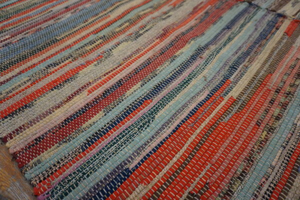 Chunky flatweave rag rug with horizontal stripes of woven red, blue, gray, and multicolored fabric pieces.