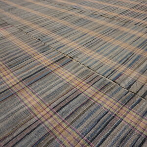 Flatwoven plaid rug in muted tones of blue, gray, and tan, accented with thin pink stripes.