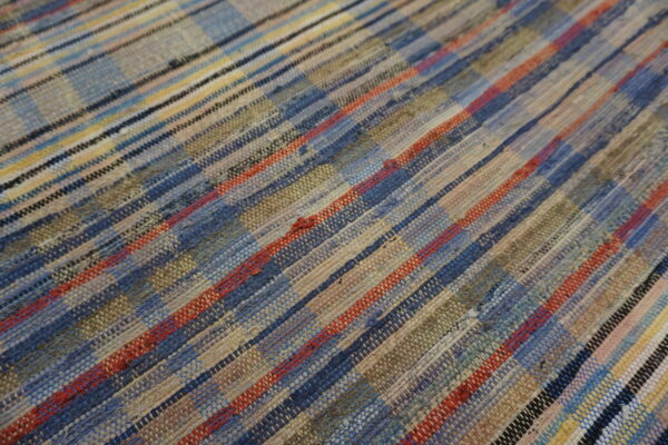 Textured, flat-weave rug featuring multi-width stripes of blue, beige, red, and green textile remnants.