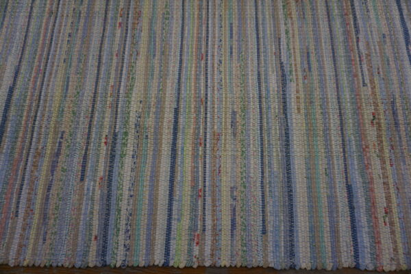 Multicolor flatweave rug with thin vertical stripes resting on a dark brown wooden floor.