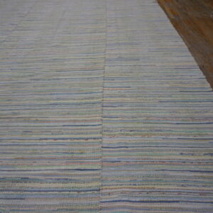 Lightly colored flatweave rug featuring thin horizontal stripes of blue, cream, green, and pink tones on wood flooring.