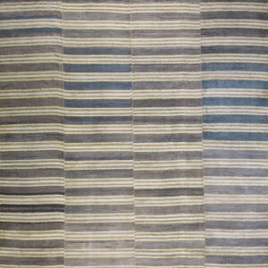 The rug displays horizontal stripes and joined vertical panels in shades of gray, slate blue, and pale green.