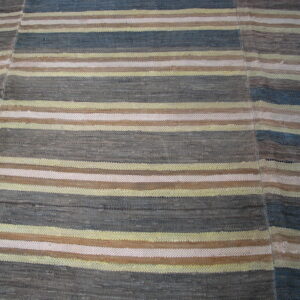 A flatwoven striped rug featuring colors of gray, blue, brown, pale yellow, and off-white visible across stitched panels.