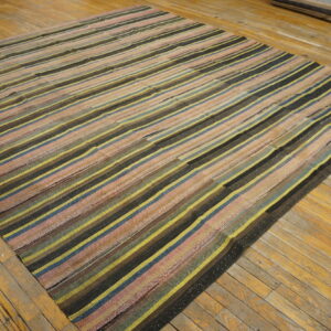 Highly textured, multicolored striped flatweave rug displayed on glossy, aged wood plank flooring.