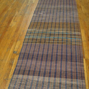 Flatwoven American Rag Rug runner in navy, rust, and gray stripes with a turquoise plaid section on wood flooring.
