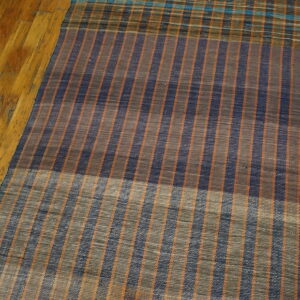 Navy, brown, and orange striped flatweave hallway runner resting on glossy, worn wooden floorboards.