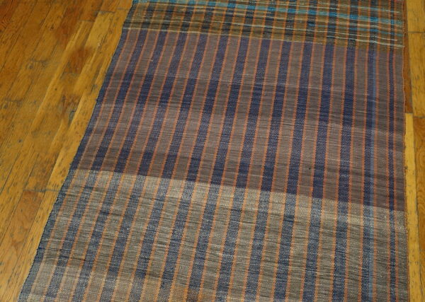 Vintage american rag rug hallway runner multicolor 1950s 3 Navy, brown, and orange striped flatweave hallway runner resting on glossy, worn wooden floorboards.