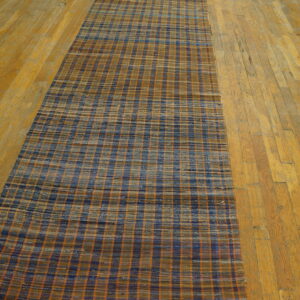 Flatweave hallway runner with a blue, brown, and orange checked pattern on wide plank hardwood flooring.