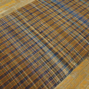 Flatwoven plaid runner rug in brown, blue, and orange on distressed yellow wooden planks.
