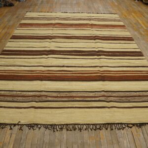 Cream flatweave rug with horizontal stripes of dark brown and rusty red on distressed wood floor.