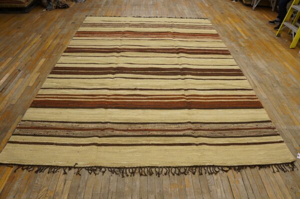 Cream flatweave rug with horizontal stripes of dark brown and rusty red on distressed wood floor.