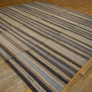 Striped, multicolored patchwork flatweave rug rests on a weathered wood floor.
