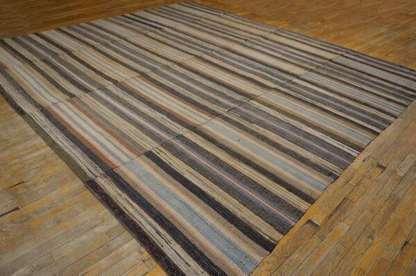 Striped, multicolored patchwork flatweave rug rests on a weathered wood floor.