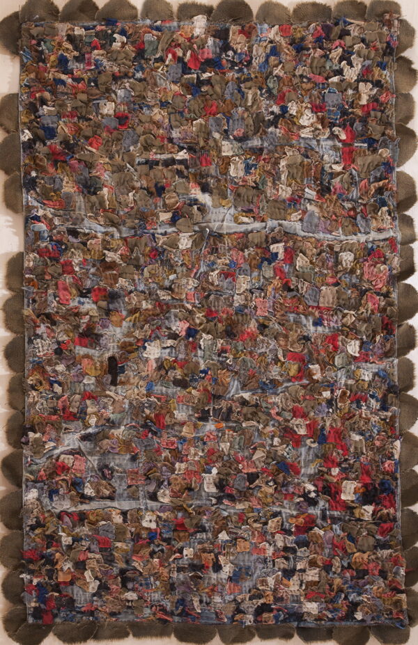 Highly textured rag rug with multicolored scraps and a contrasting dark scalloped edge displayed vertically.