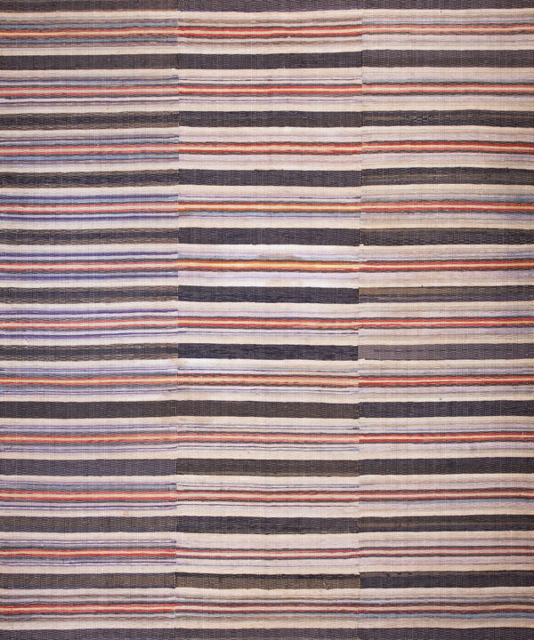 Muted flatweave rug with wide and thin horizontal stripes of dark blue, cream, red, and lavender.