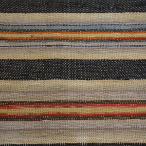 A chunky woven rug features horizontal stripes in navy, beige, purple, red, orange, and assorted muted colors.