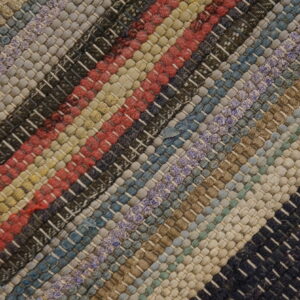 Diagonal multicolored striped rug featuring a thick, chunky woven texture in red, blue, tan, and black.