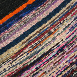 Low-pile diagonal striped rag rug featuring dense weaves of multicolored fabric strips.