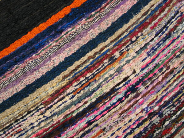 Low-pile diagonal striped rag rug featuring dense weaves of multicolored fabric strips.