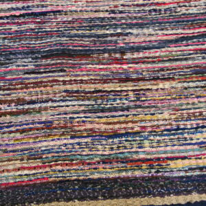 Flat-woven, multicolored rag rug with chunky horizontal stripes lies on wood planks.