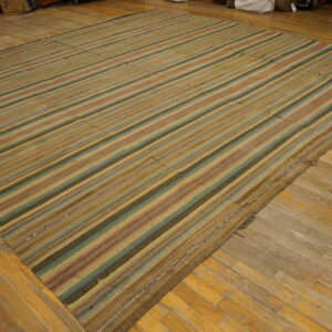 Flatwoven rug featuring wide vertical stripes in tan, muted green, and red on distressed hardwood flooring.