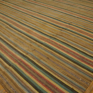 Flatweave striped rug in tan, teal, red, and dark brown, showing panel seams on hardwood floor.
