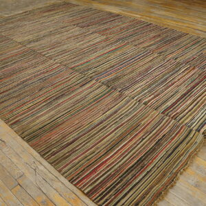 Large, flatwoven rug with multicolor vertical stripes lies on rustic, light-colored wood flooring.