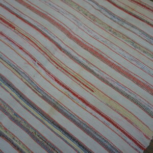 Low-pile white rug featuring narrow red, yellow, blue, and variegated multicolor stripes on wood planks.