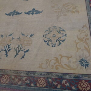 Cream rug with scattered gold and blue florals, featuring a complex burgundy border over dark wood flooring.