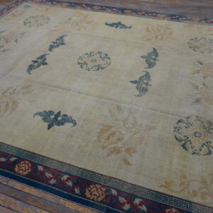 Large beige rug featuring floral patterns in teal and gold on rustic wooden floorboards.