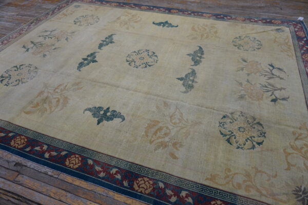 Large beige rug featuring floral patterns in teal and gold on rustic wooden floorboards.
